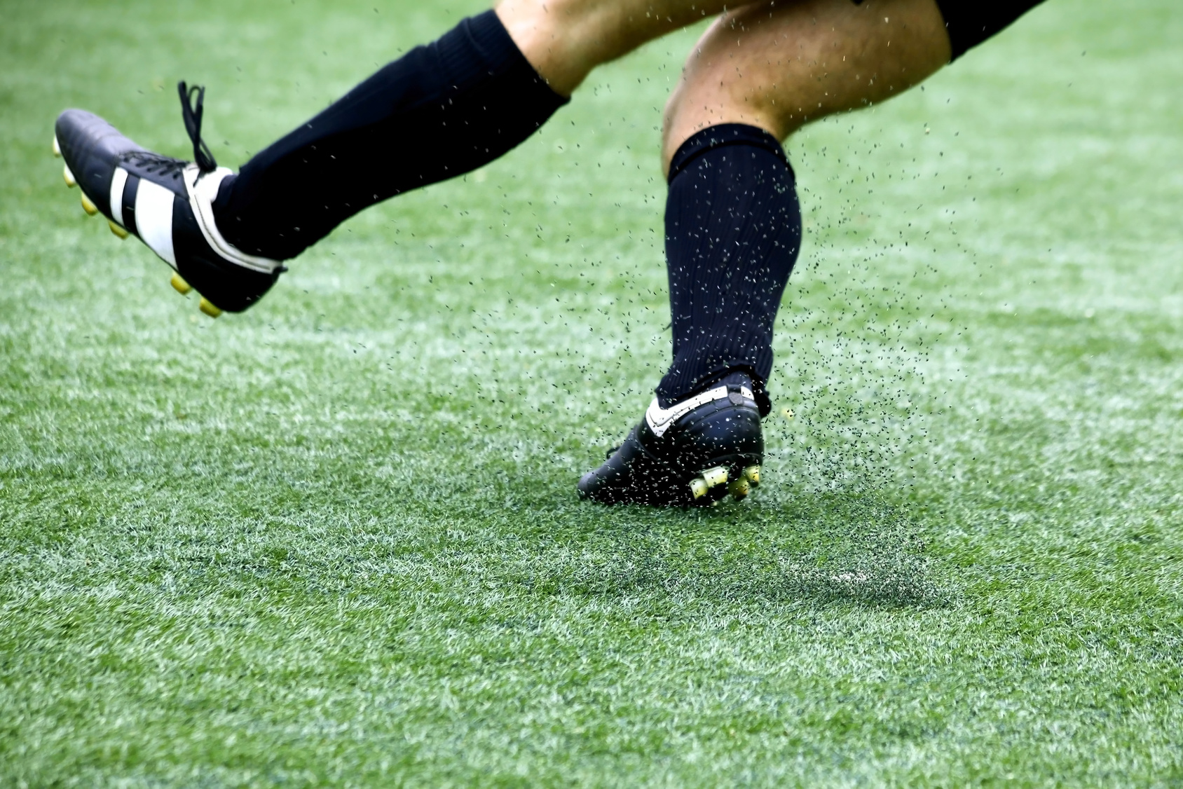 Image of an athlete on Synthetic Turf, kicking up crumb rubber pellets